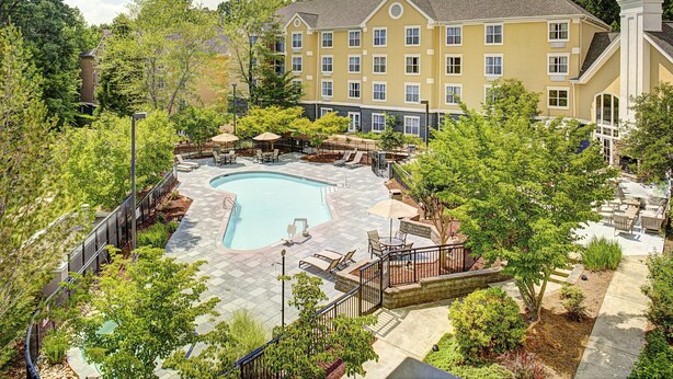 A hotel with a swimming pool, outdoor seating, and a garden area.