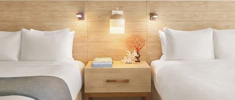 A hotel room with two beds, a nightstand with a lamp, and a small decorative plant.
