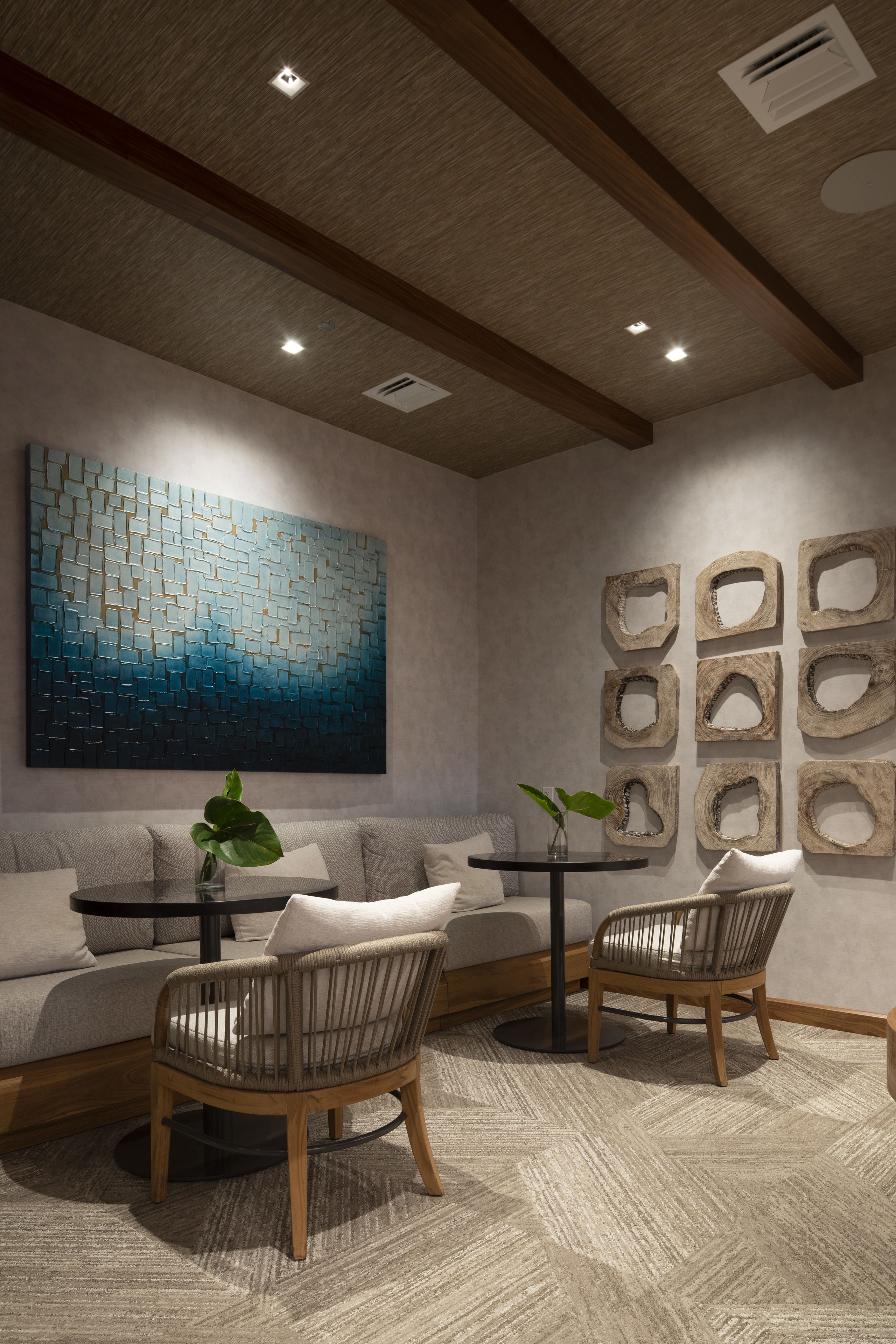 A modern living room with a sofa, two chairs, a coffee table, and a large abstract painting.