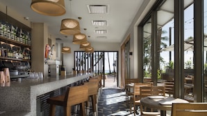 Una zona de bar moderna con una barra larga, taburetes de madera y un suelo estampado.