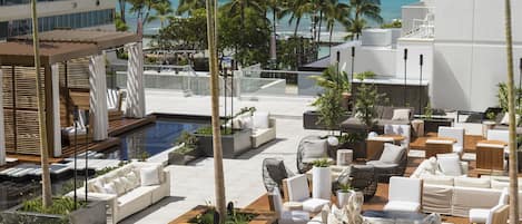 A rooftop lounge with outdoor seating, a pool, and a view of the ocean.
