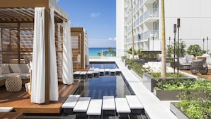 A rooftop pool area with a view of the ocean, wooden deck seating, and modern outdoor furniture. - 'Alohilani Resort Waikiki Beach (Honolulu)