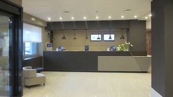 A reception area with a modern design, featuring a reception desk, seating area, and a large window.
