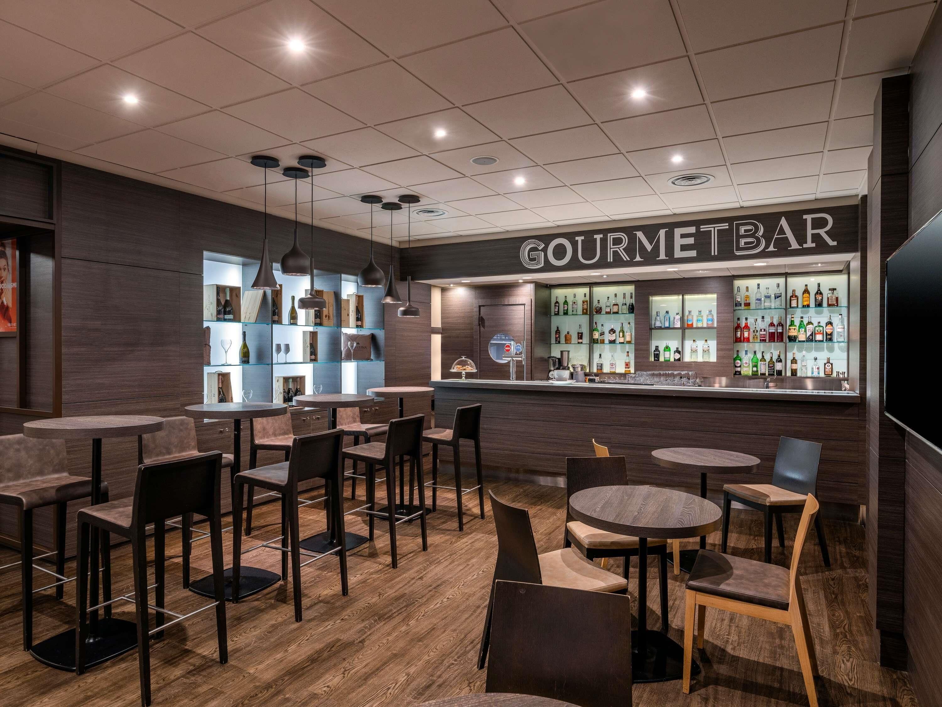 A bar area with multiple seating options, a bar counter, and shelves with bottles.