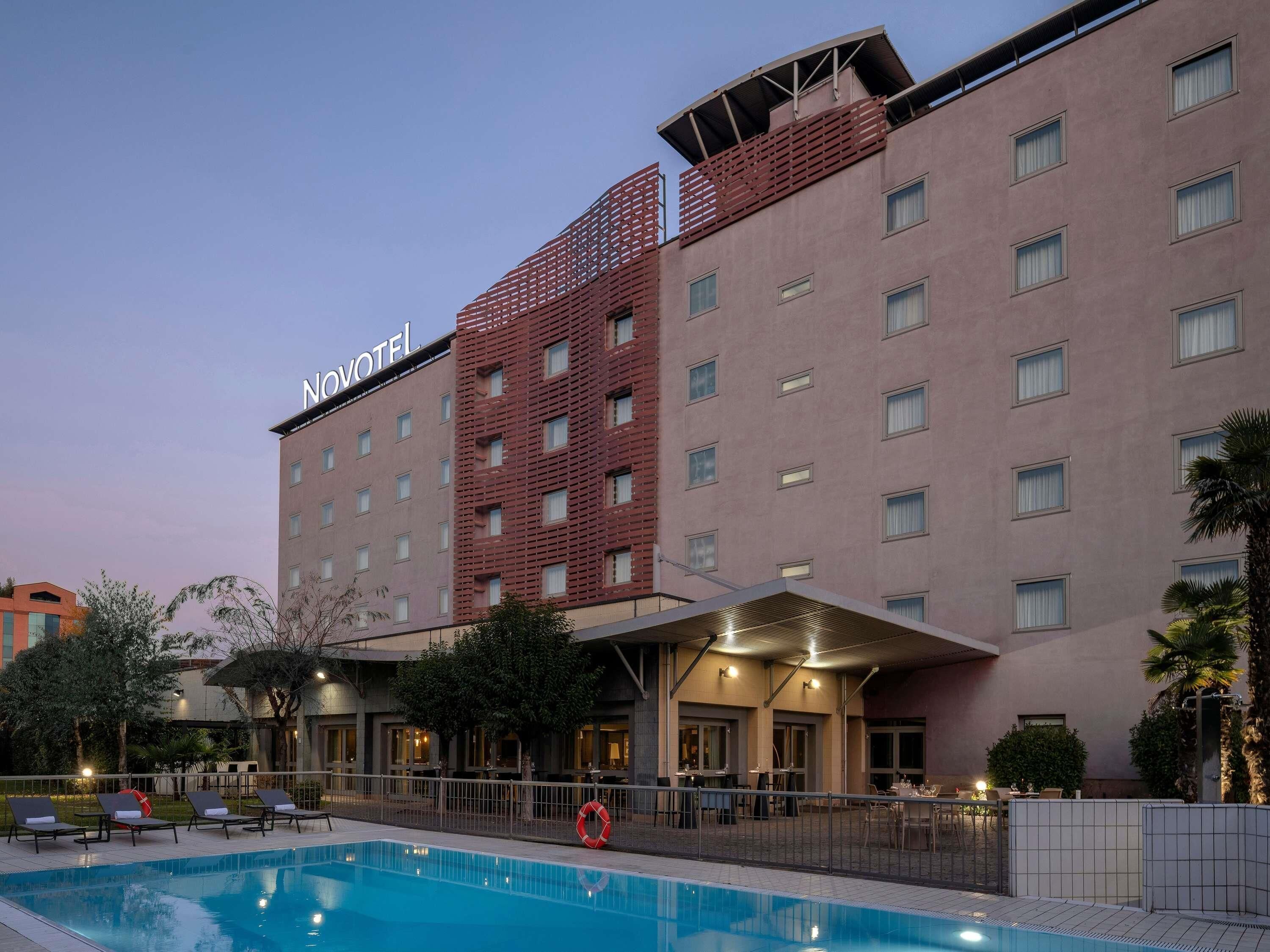 Un hotel con piscina, area salotto esterna e zona coperta.