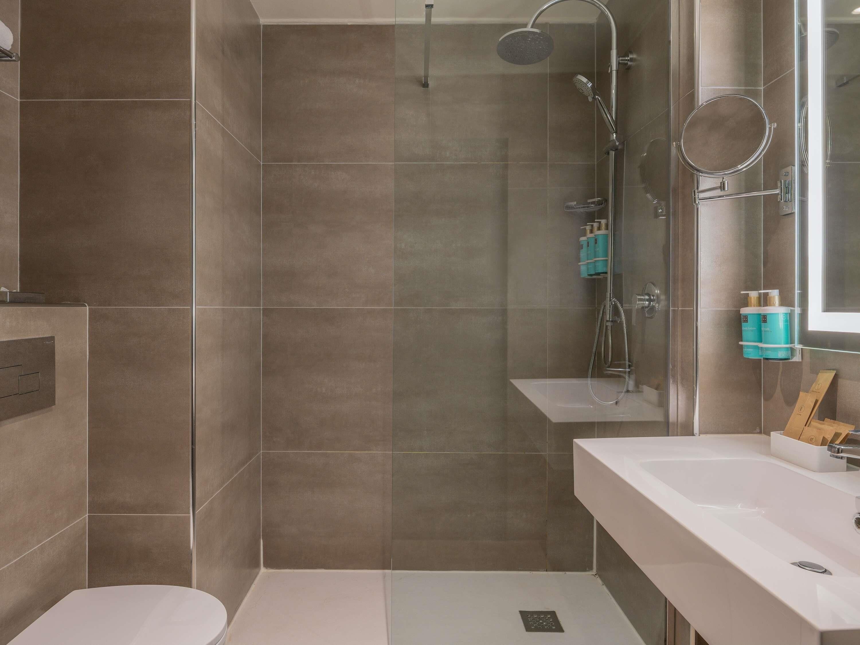 A modern bathroom with a shower, toilet, and sink.