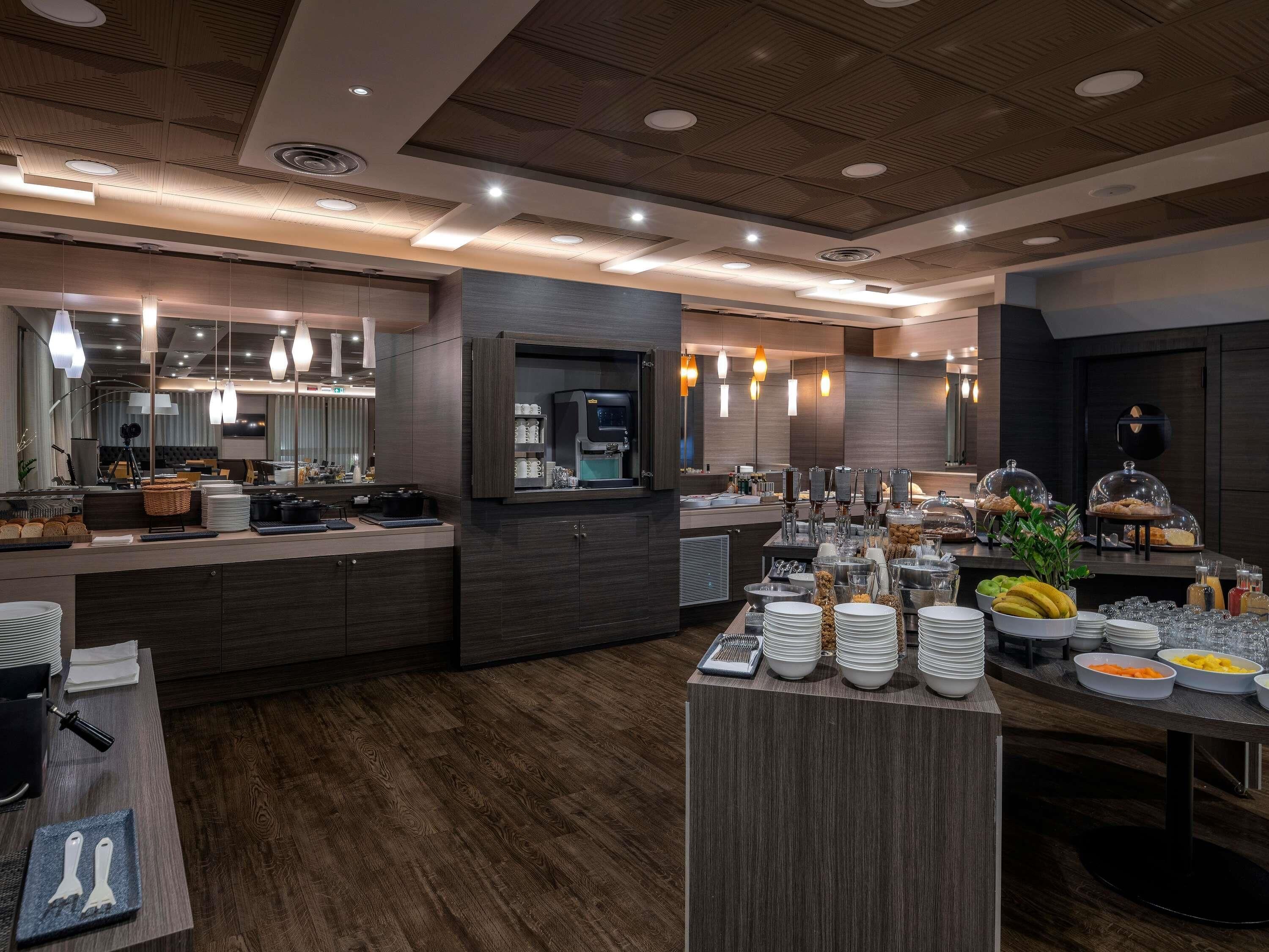 Una cocina de hotel moderna con un sistema de bufé, que incluye una máquina de café, fruteros y una variedad de alimentos.