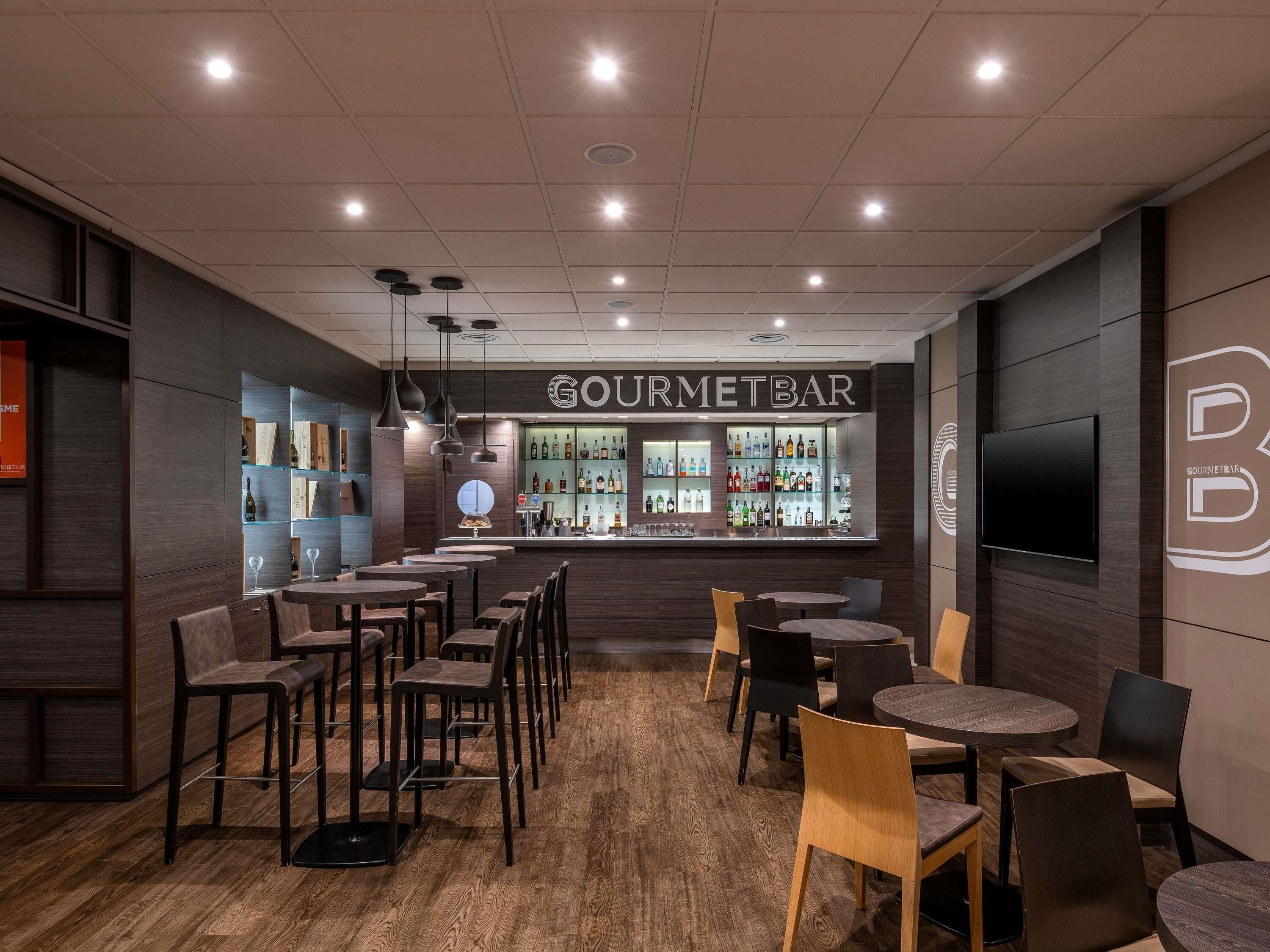 L’intérieur d’un restaurant, avec un espace bar, un plancher en bois et un éclairage moderne.