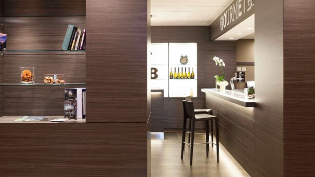 A modern bar area with a wooden interior, a counter, and a seating area. - Novotel Brescia 2 (Brescia)