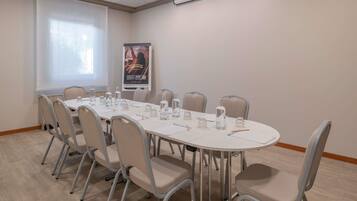 Une salle de conférence avec une longue table, des chaises, des bouteilles d’eau et une affiche accrochée au mur.