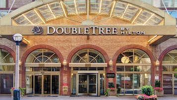 De gevel van het DoubleTree by Hilton hotel met een opvallende ingang, gebogen ramen en een glazen luifel.