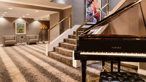 A grand piano in a spacious living area with a carpeted staircase and a large painting on the wall. - DoubleTree by Hilton Hotel Toronto Downtown (Toronto)