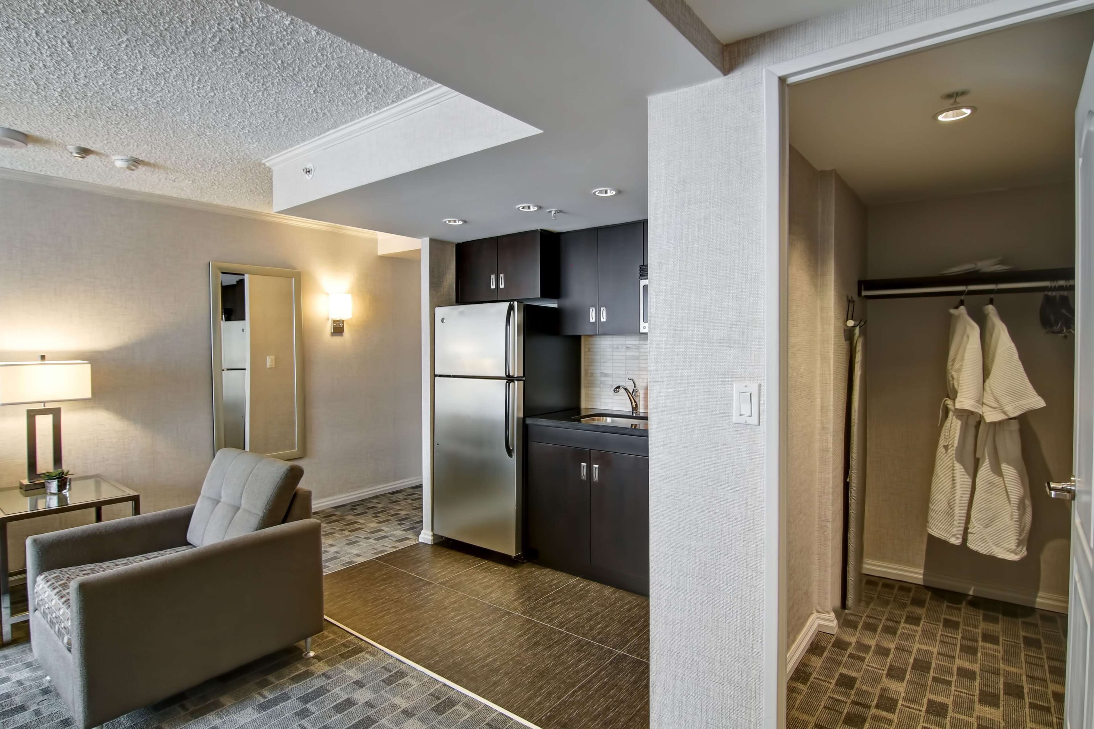 A modern kitchen with dark cabinets, a stainless steel refrigerator, and a built-in oven.