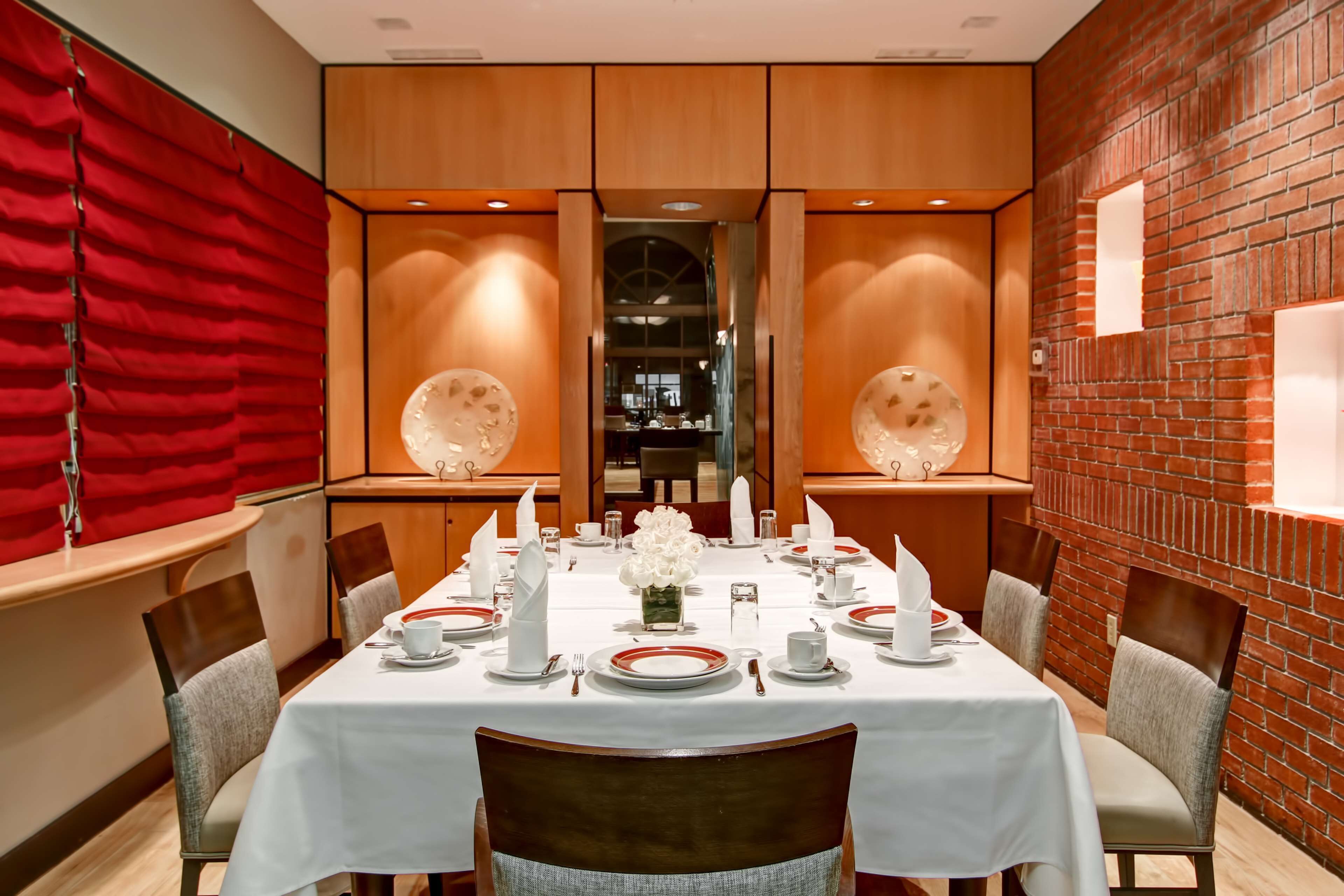 Un espace repas avec une longue table dressée pour six personnes, entourée de chaises.