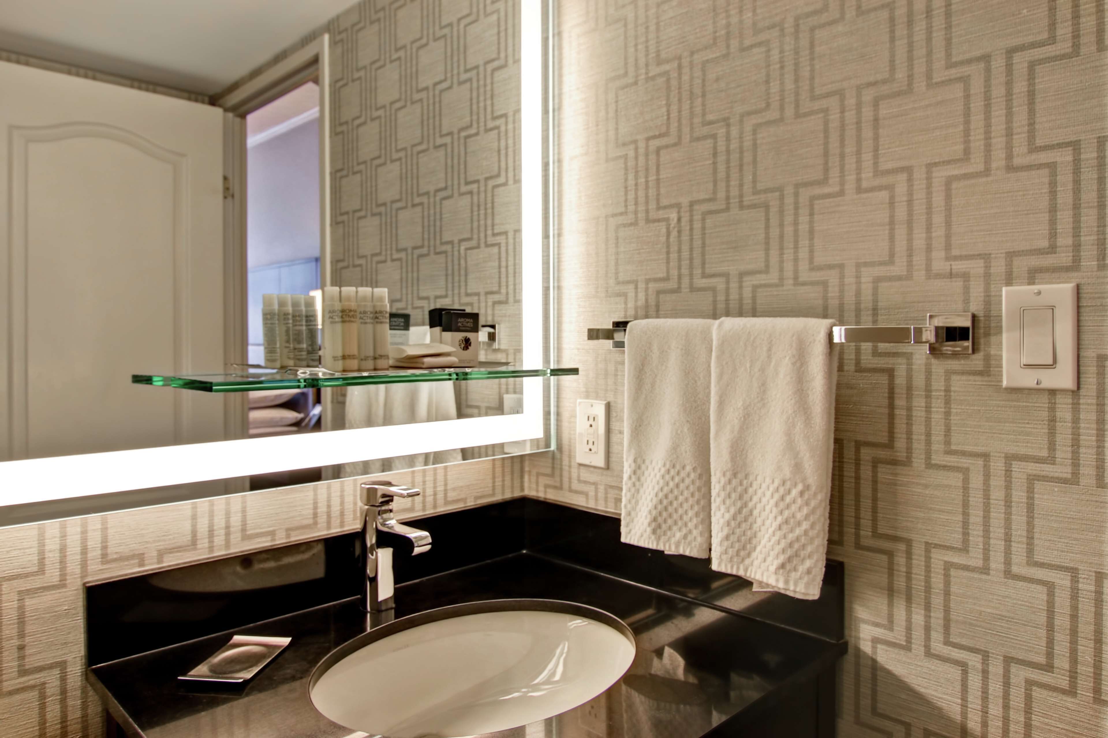 Un bagno con ripiano in vetro, un lavabo rotondo e un asciugamano su un porta-asciugamani.