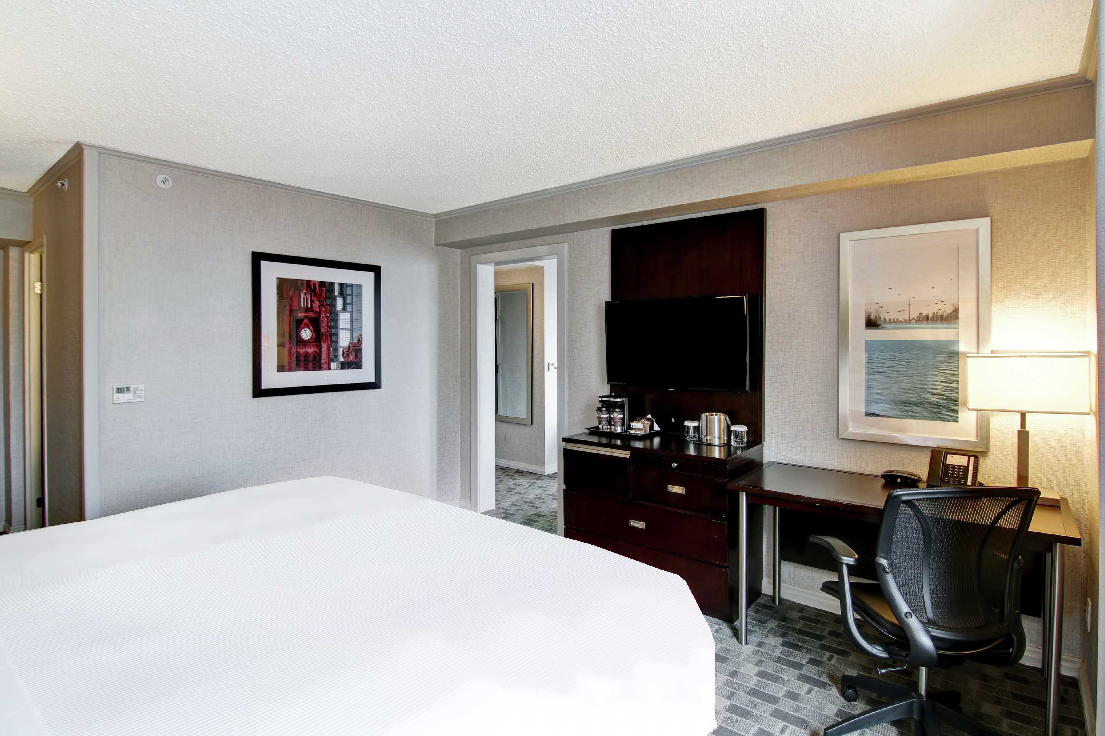 A hotel room with a large bed, a desk with a chair, a television, and a coffee maker.
