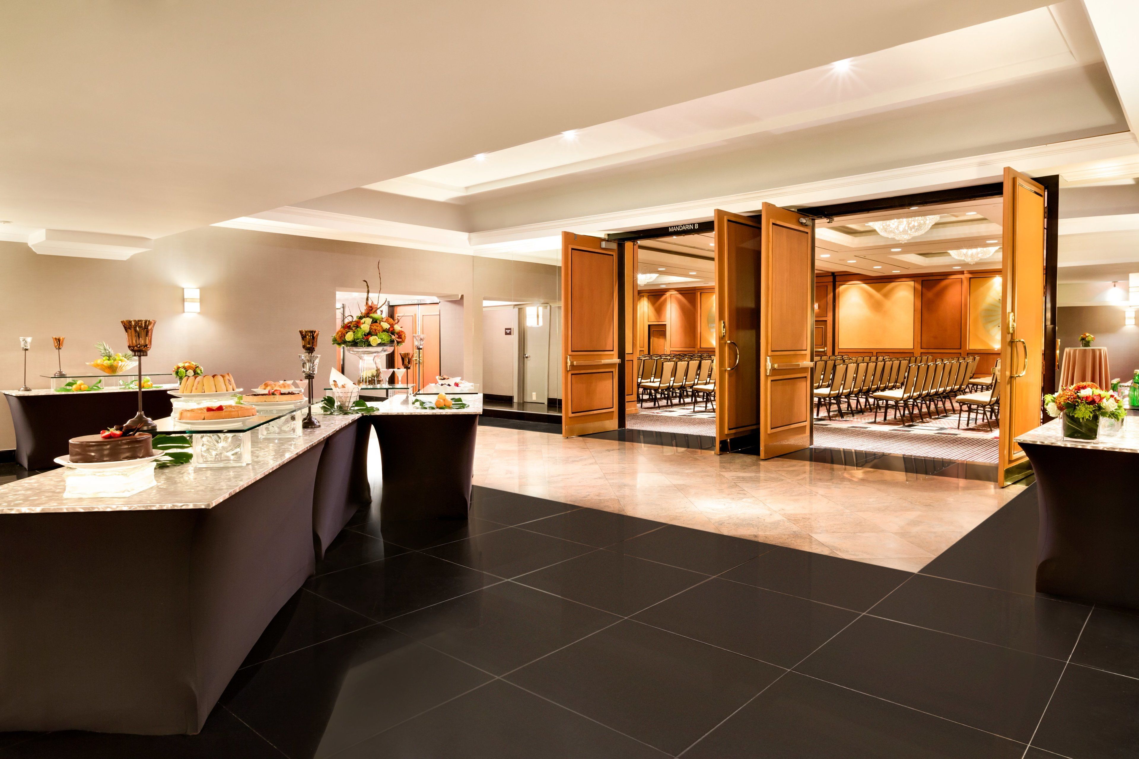 Un amplio vestíbulo de hotel con mostrador de recepción, zona de estar y vistas a un salón de banquetes.