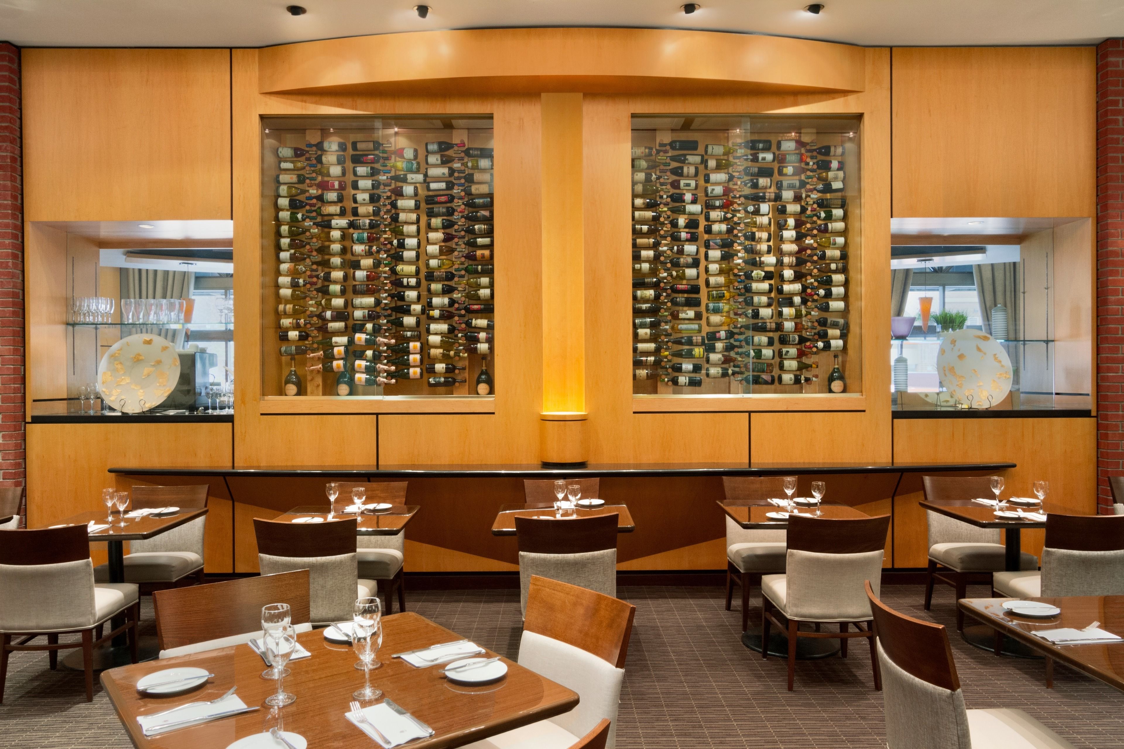 A restaurant with wooden paneling, a wine wall, and tables set for dining.