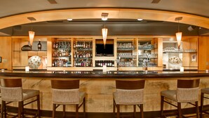 A bar area with a long counter, multiple stools, shelves with bottles, glasses, and a television. - DoubleTree by Hilton Hotel Toronto Downtown (Toronto)