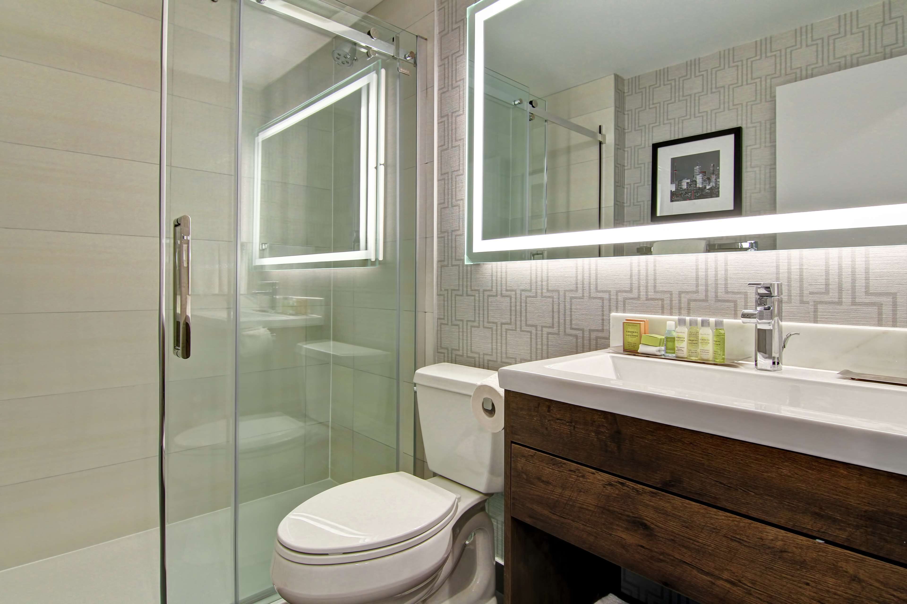 Une salle de bain moderne avec une douche à parois de verre, des toilettes et un meuble-lavabo avec un miroir au-dessus du lavabo.