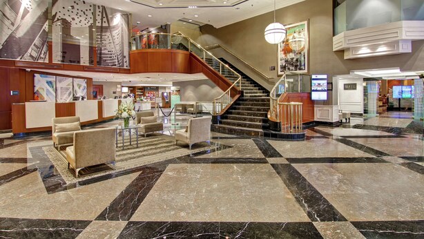 A spacious lobby with a check-in desk, seating area, and a staircase leading to upper floors. - DoubleTree by Hilton Hotel Toronto Downtown (Toronto)