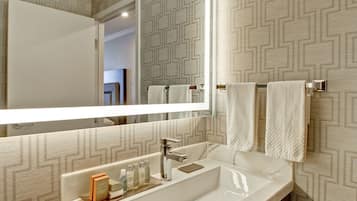 A bathroom with a large mirror, a white sink, and two towels hanging on a towel rack.