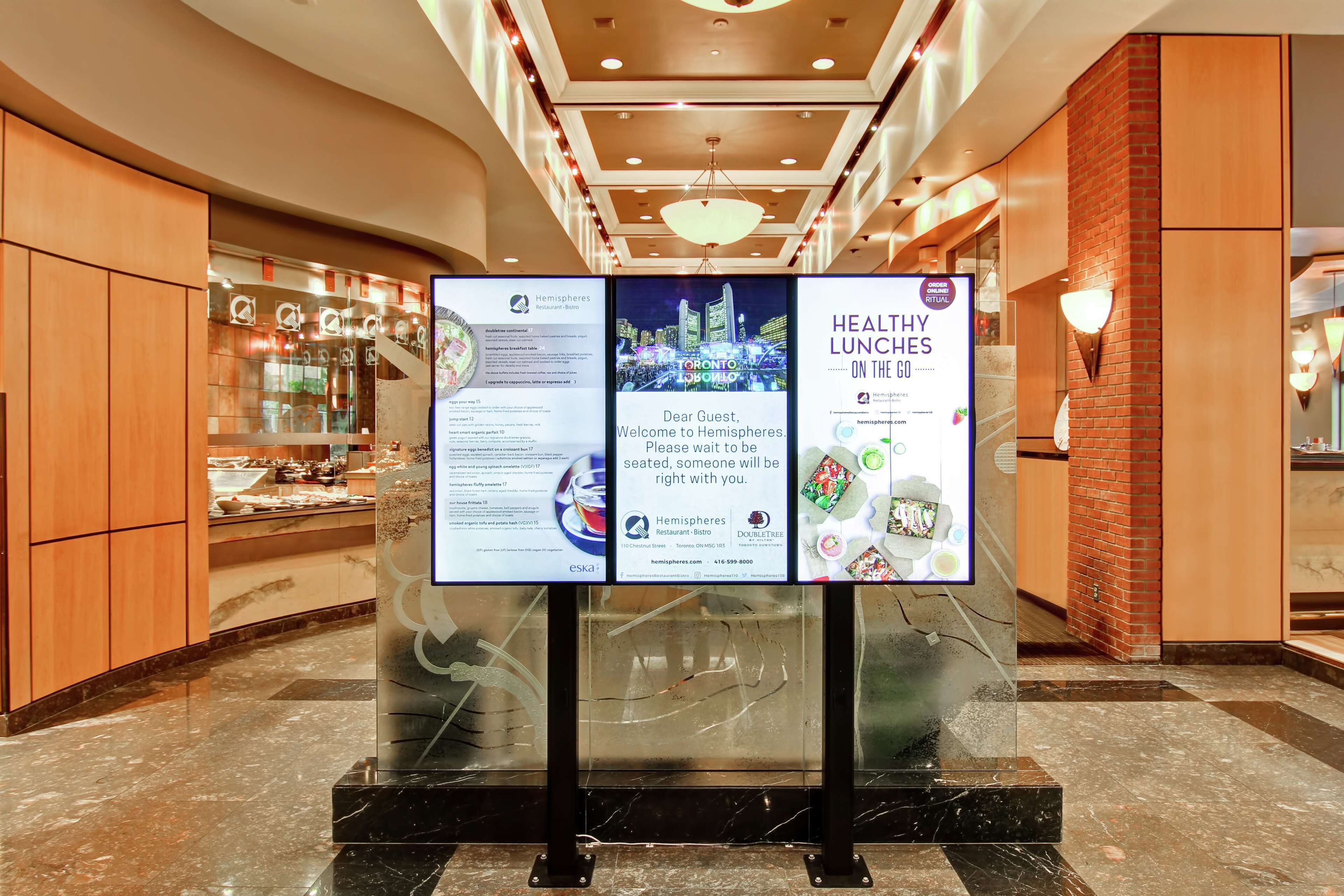 A hotel reception area with a glass display case, a reception desk, and a signboard advertising healthy lunches.