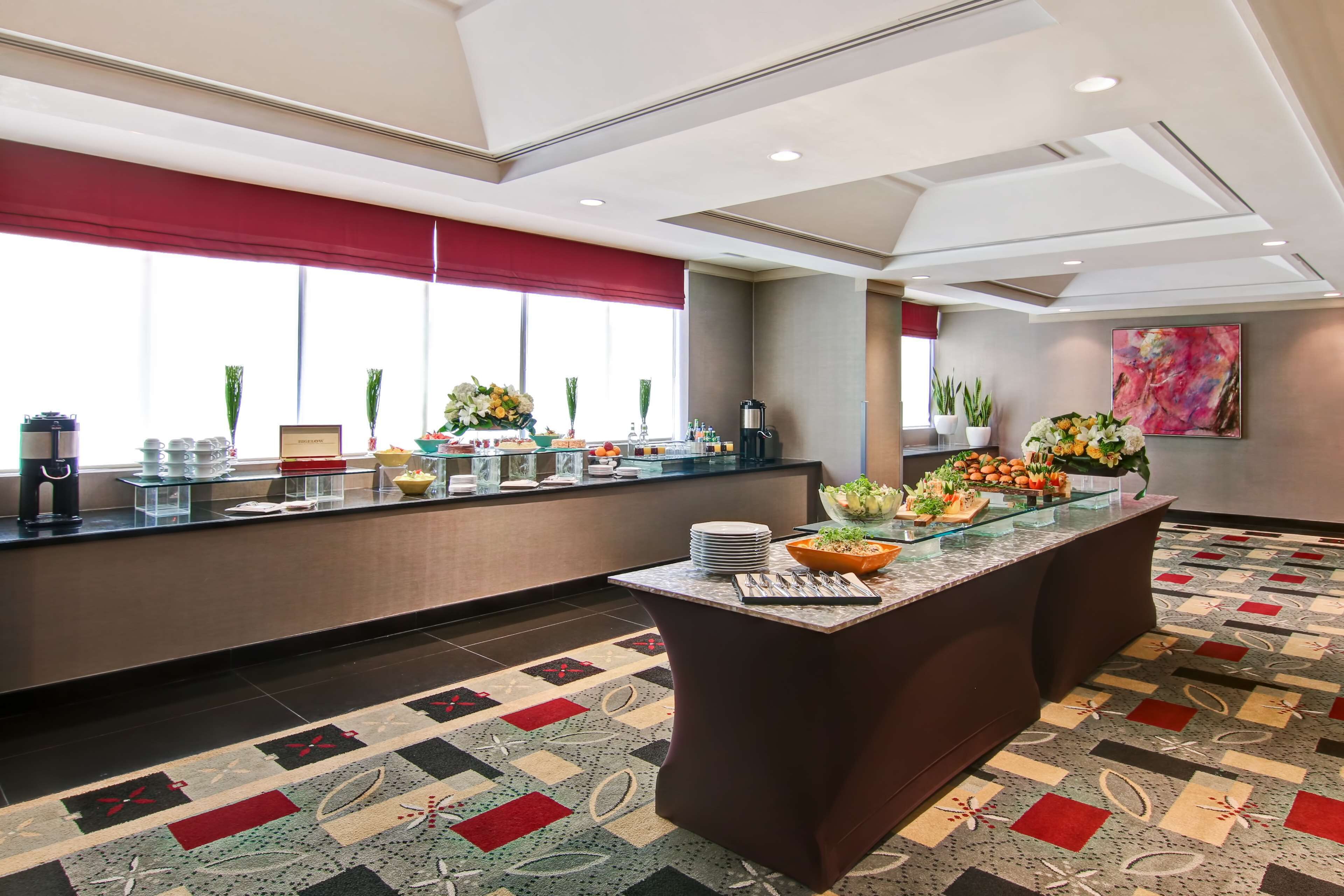 Ein Hotel-Empfangsbereich mit einem Buffet, dekorativen Pflanzen und einem gemusterten Teppich.