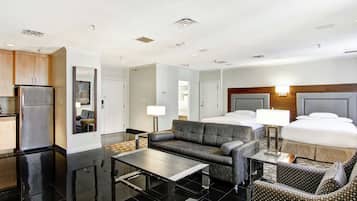Een moderne hotelkamer met kitchenette, een bank, een eettafel en een bed met hoofdeinde.