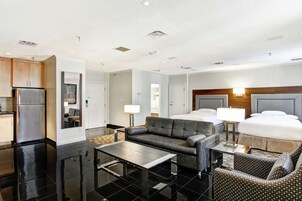 Een moderne hotelkamer met kitchenette, een bank, een eettafel en een bed met hoofdeinde.