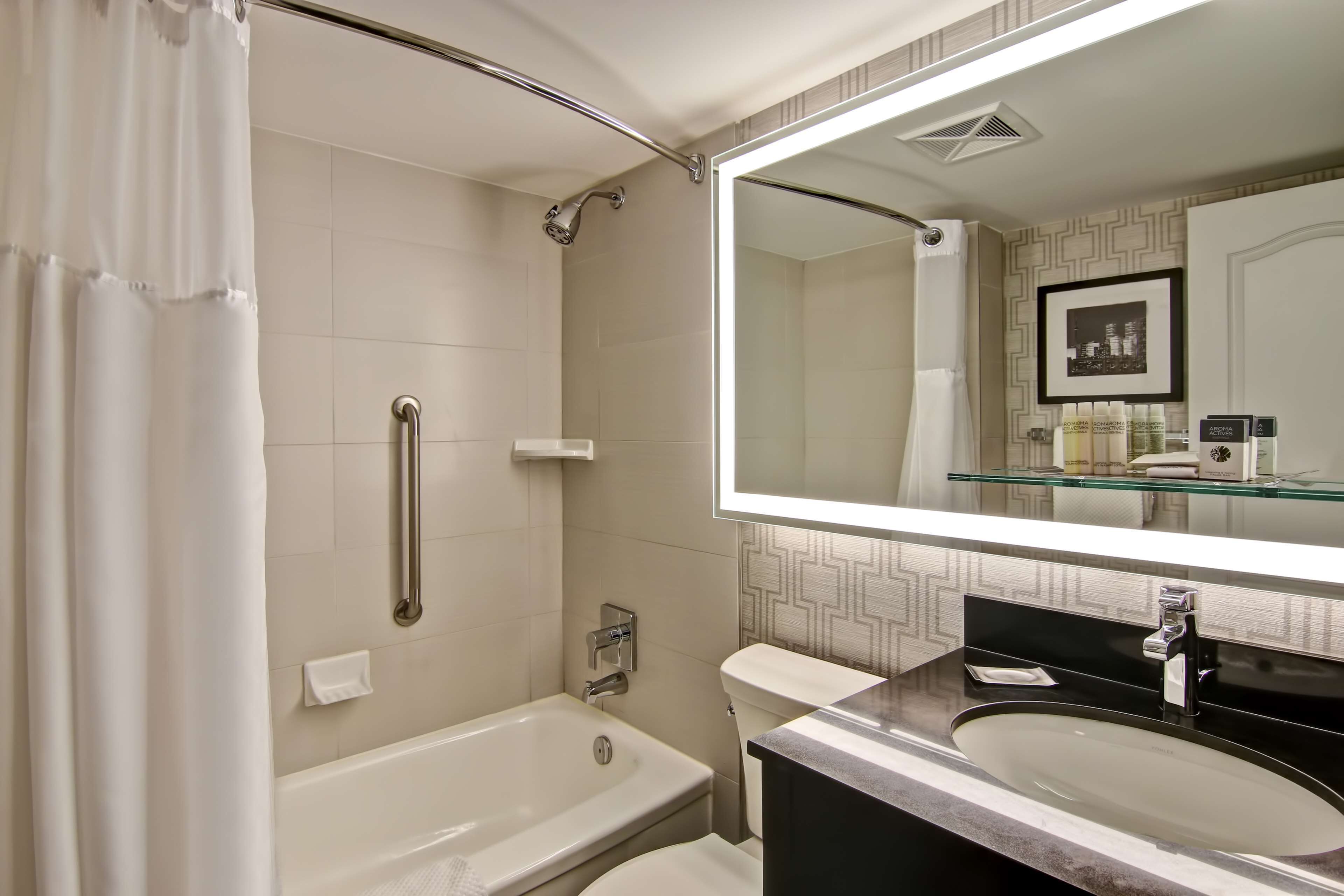 Een moderne badkamer met een badkuip, toilet en een grote spiegel boven de wastafel.