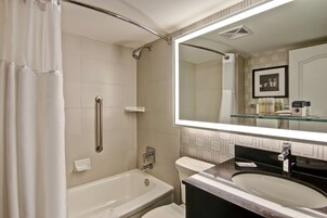 Een moderne badkamer met een badkuip, toilet en een grote spiegel boven de wastafel.