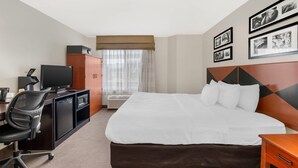 A hotel room with a bed, a desk with a computer, a television, a wardrobe, and framed pictures on the wall. - Sleep Inn Billings (Billings)