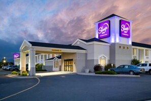 A Sleep Inn by Choice Hotels with a clear entrance, a parking lot, and a well-lit building facade.
