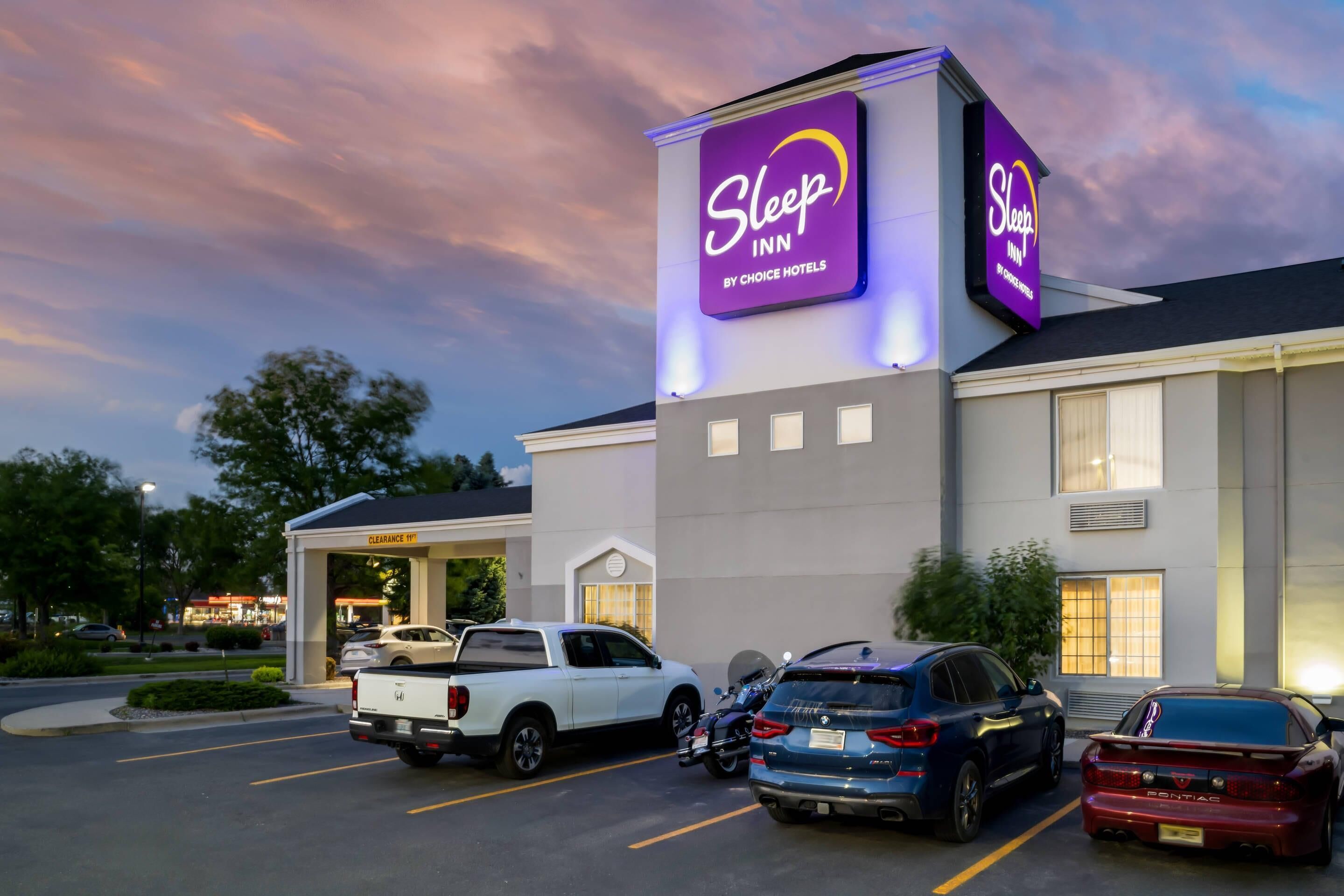 Un bâtiment de la chaîne Sleep Inn, qui fait partie du groupe Choice Hotels, avec un parking où sont stationnés divers véhicules.