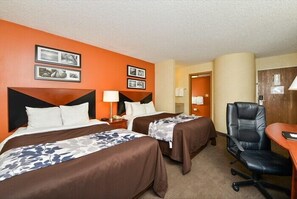 A hotel room with two beds, a desk, a chair, and a door leading to another room.