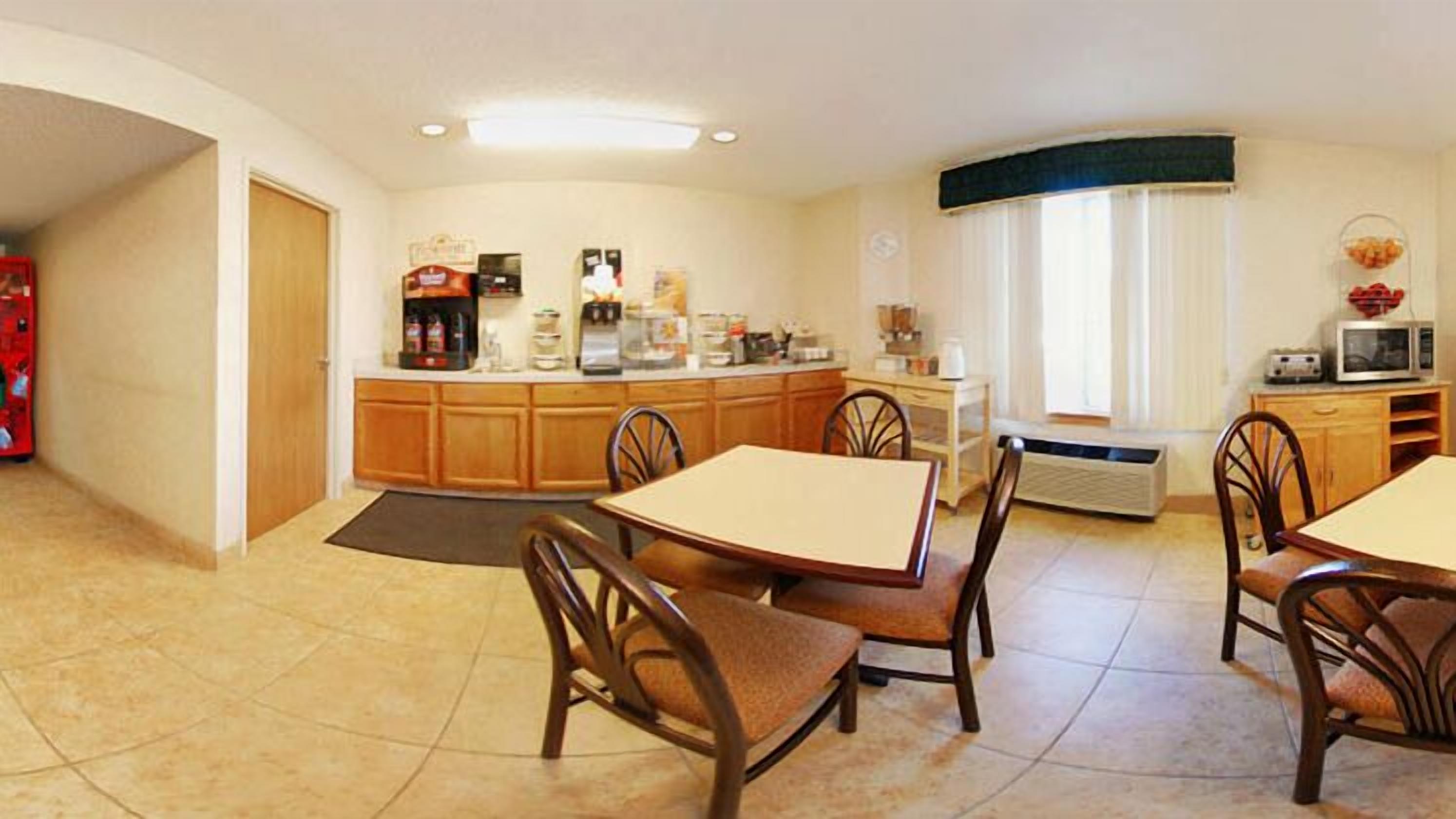 A compact kitchen with a dining area, featuring a central island, wooden cabinets, and basic appliances.