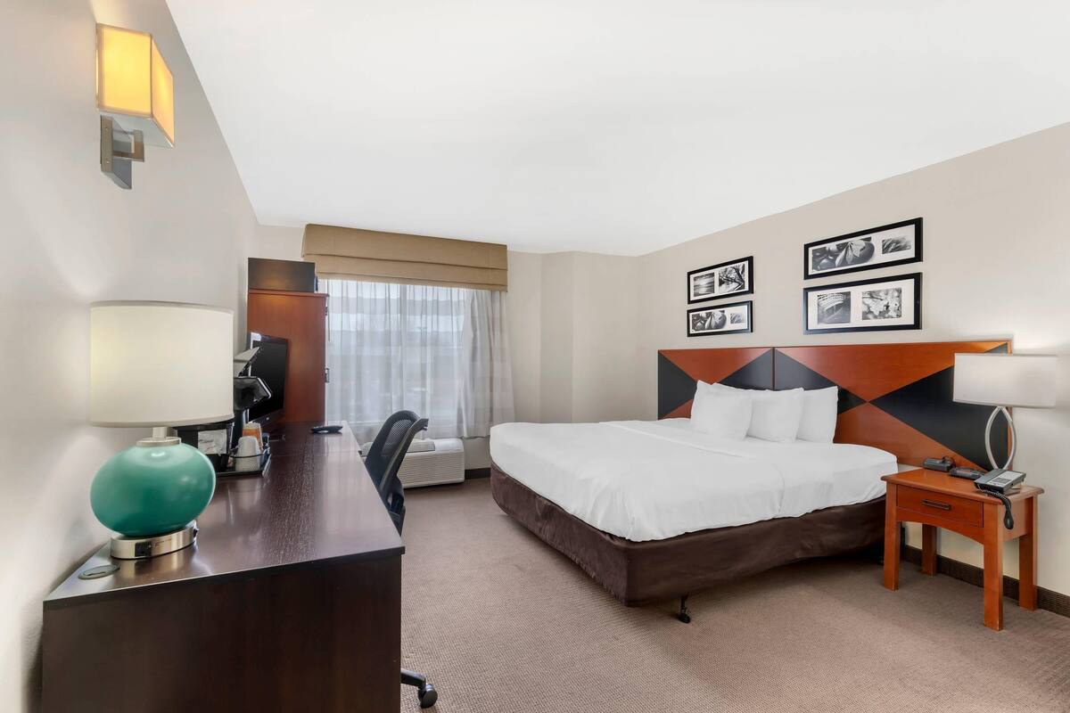Une chambre d’hôtel équipée d’un lit, d’un bureau, d’une chaise et d’une table de chevet.