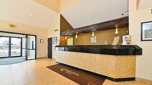 A reception desk with a 'Welcome' mat, an exit sign, and framed pictures on the wall. - Sleep Inn Billings (Billings)