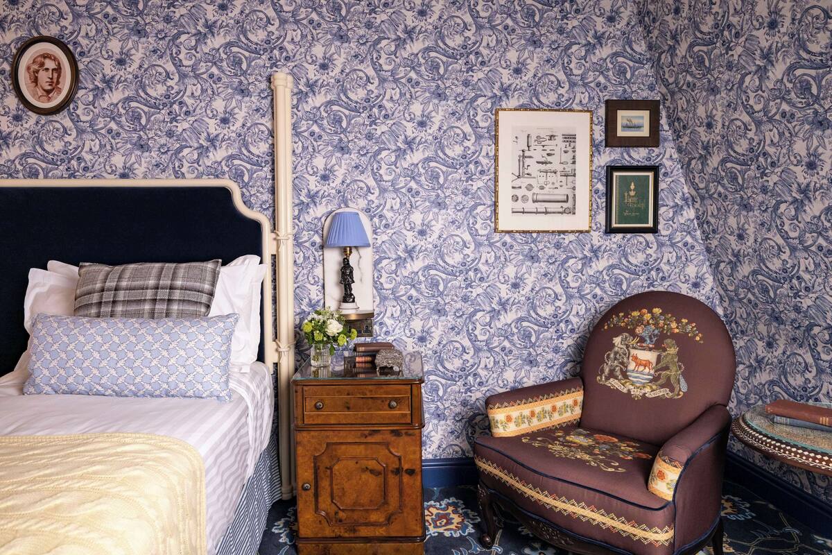 A bedroom with a bed, dresser, chair, and wall decorations.