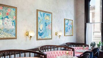 A dining area with pink upholstered booths, a round table, and wall-mounted light fixtures.