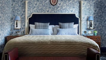 A bedroom with a large bed, two nightstands, a dresser, a mirror, and a wall with a floral pattern.