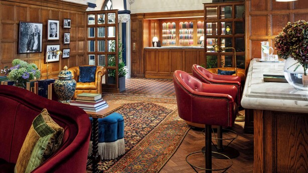 A library with bookshelves, leather chairs, and a chandelier.
