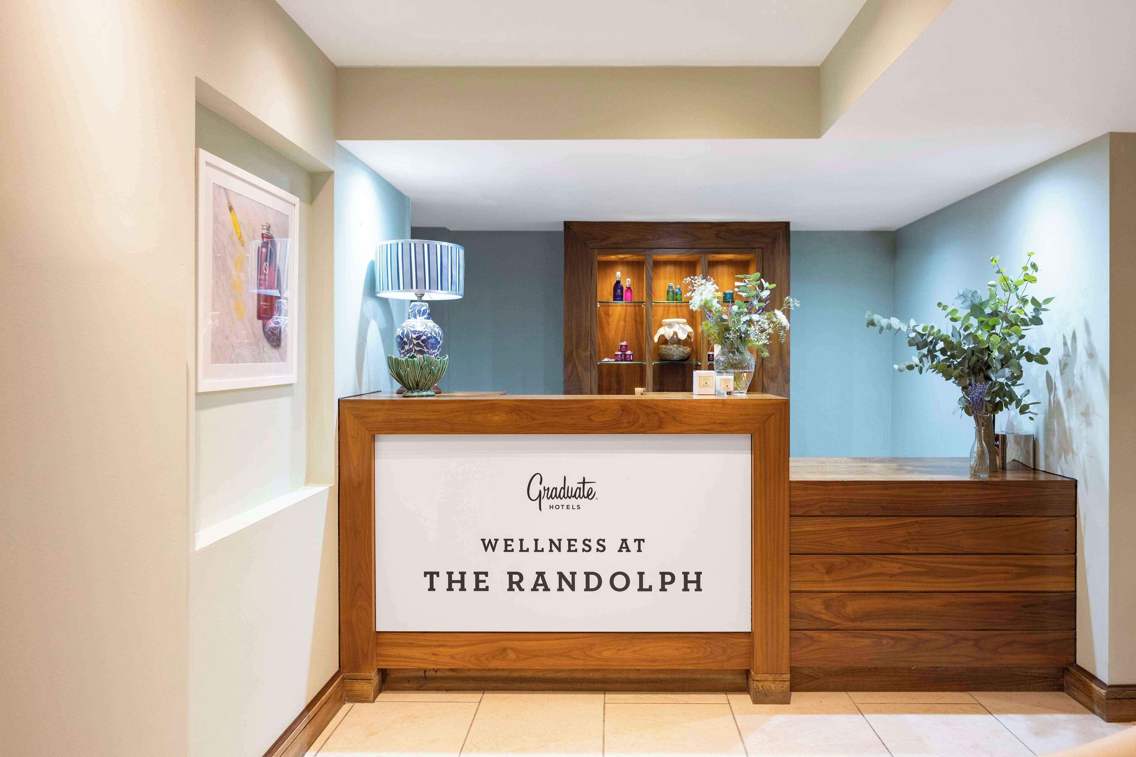 A reception desk with a sign reading "Graduate Hotels Wellness at The Randolph."