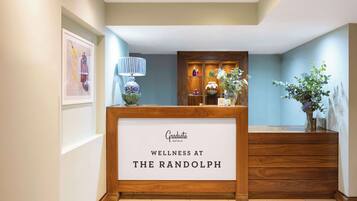 A reception desk with a sign reading "Graduate Hotels Wellness at The Randolph."