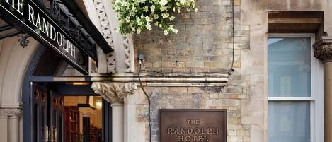 A green bicycle parked in front of The Randolph Hotel, with a hanging flower basket above the entrance.