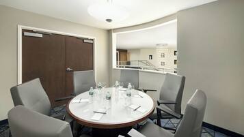 A conference room with a round table, chairs, water bottles, and a door.