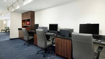A modern office space with desks, chairs, computers, and a wooden cabinet.