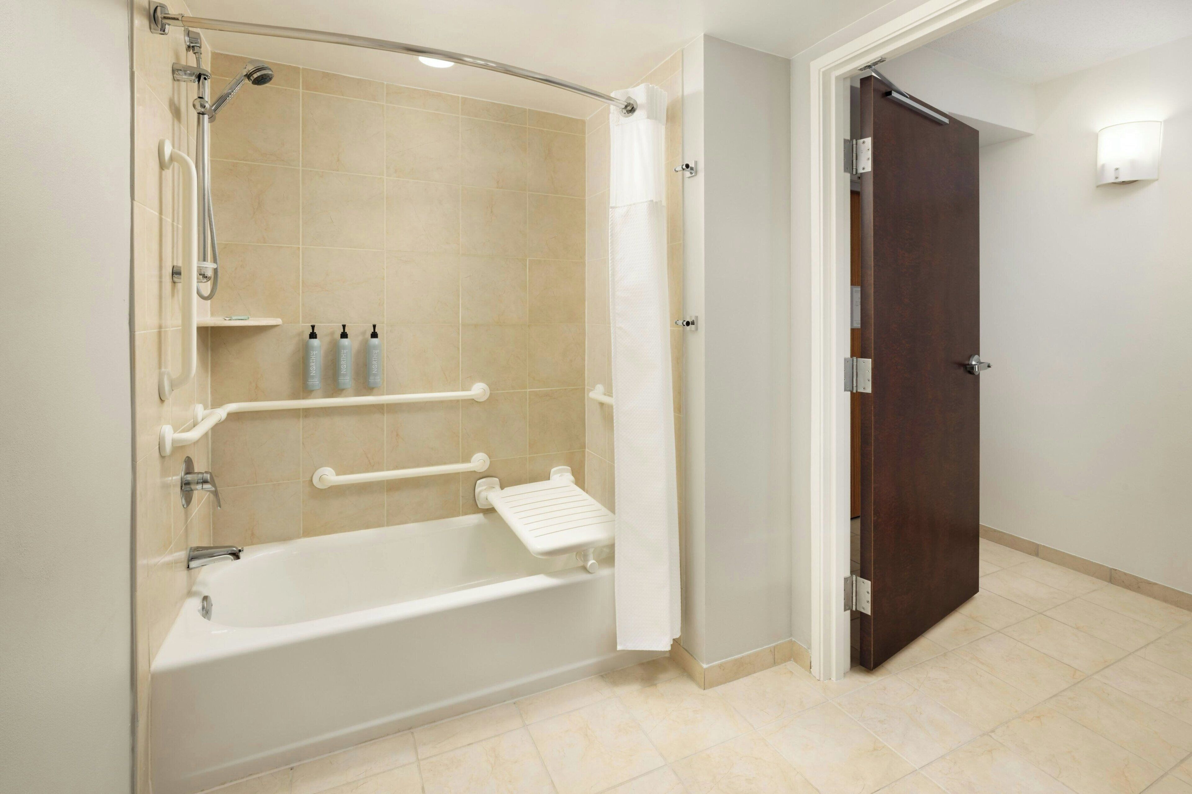A bathroom with a bathtub, shower, and a door leading to another room.