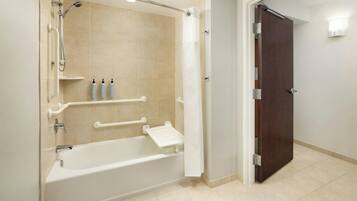 A bathroom with a bathtub, shower, and a door leading to another room.